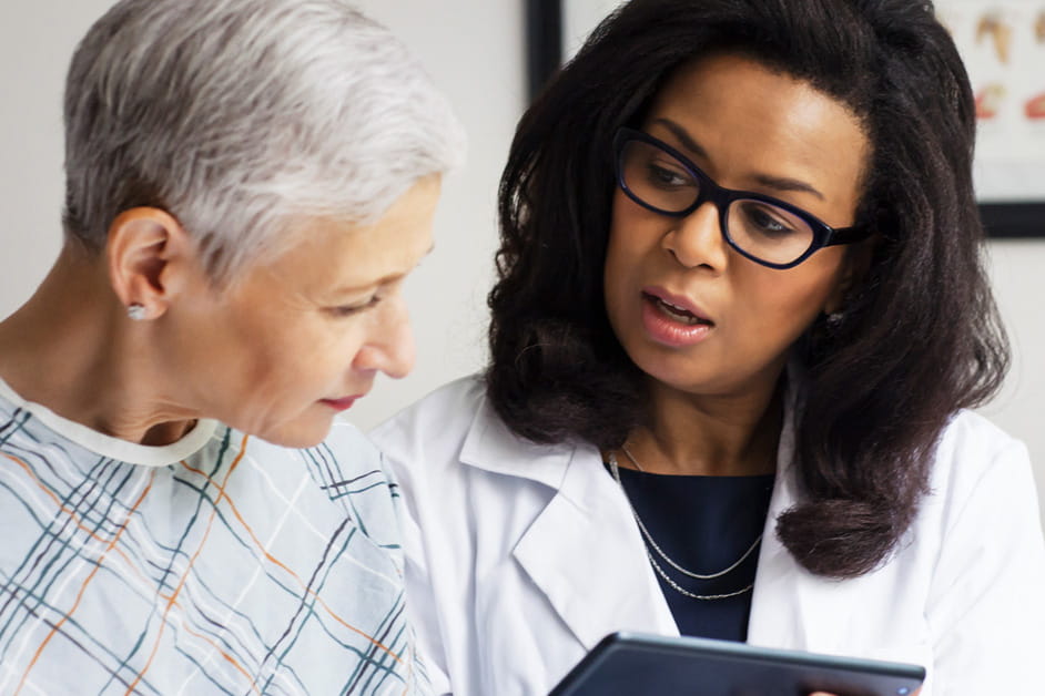 Black female doctor talking to older female patient about heart failure and transplants